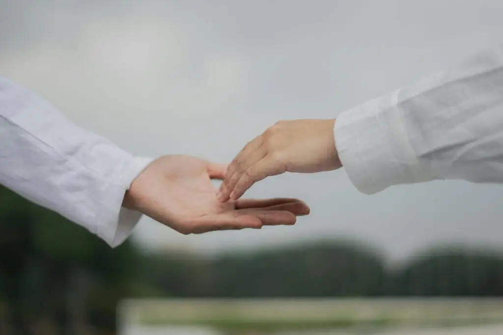 A symbolic image of two hands reaching out for connection and cooperation outdoors.